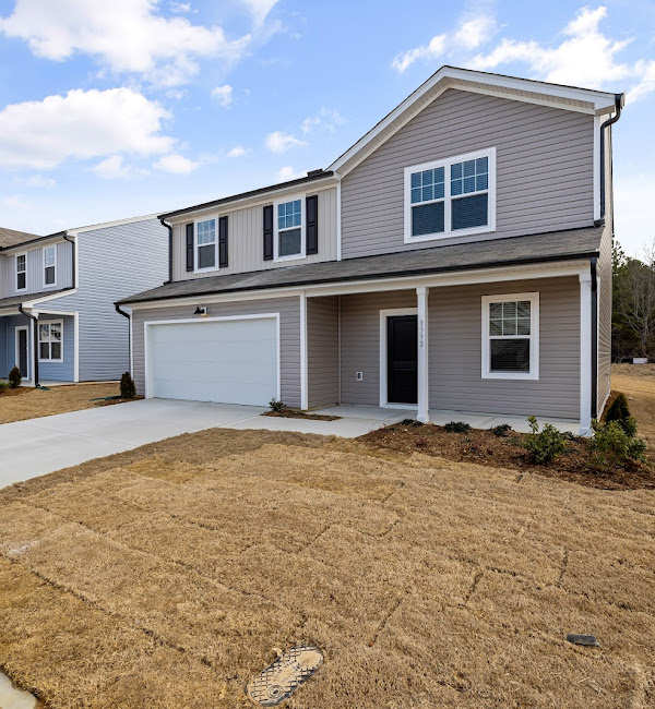 Two-car garage with white door on a gray house, daytime