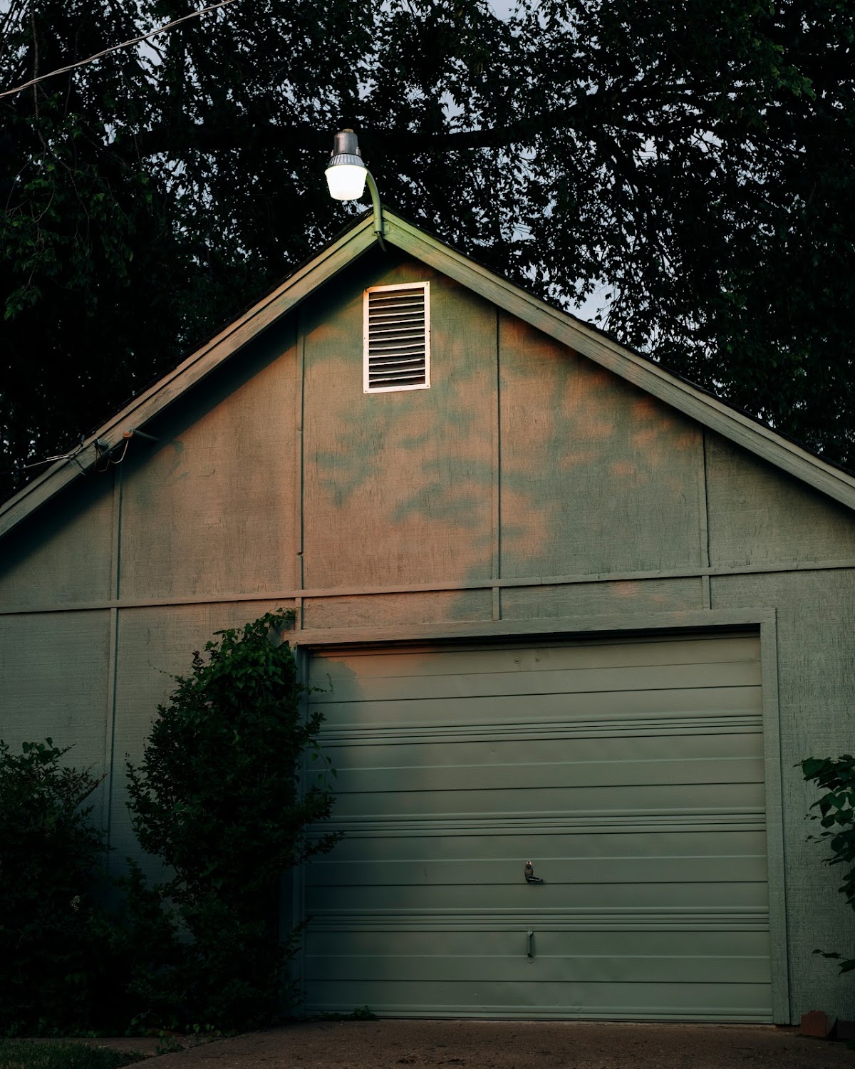 Two-car garage with white doors, dark fence, and blue sky